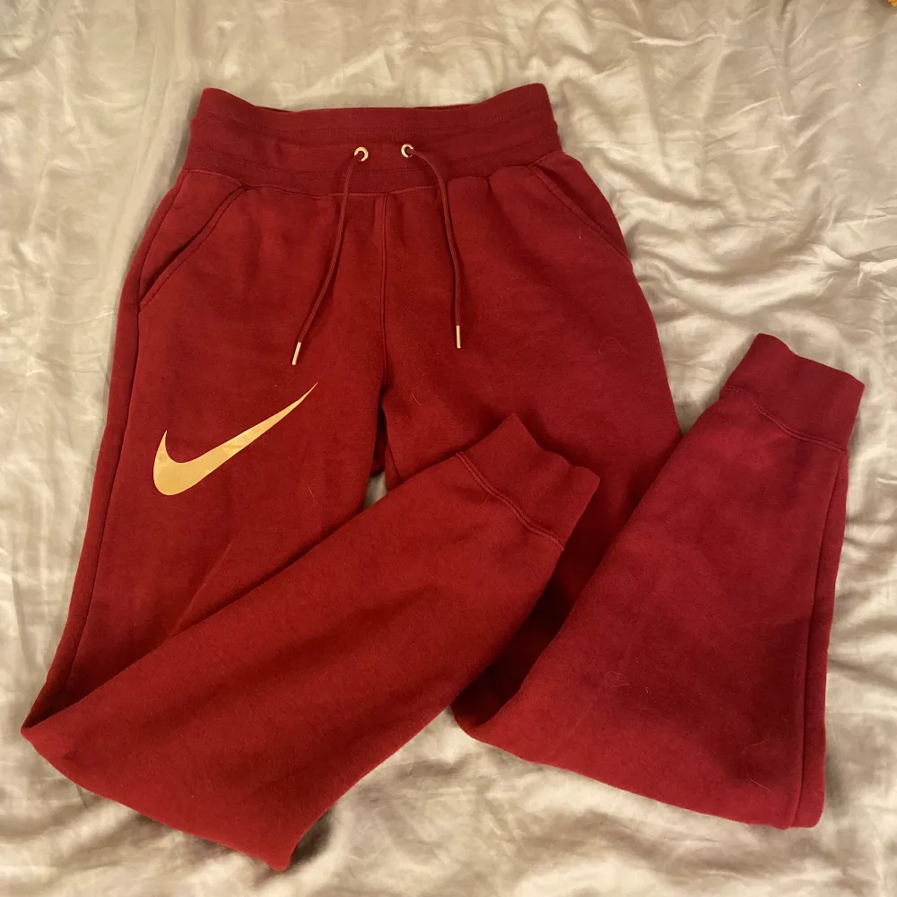 Röda sweatpants ifrån Nike med guld detaljer! Byxorna är i nyskick!. Jeans & Byxor.
