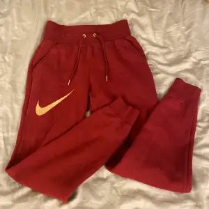 Röda sweatpants ifrån Nike med guld detaljer! Byxorna är i nyskick!