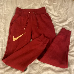 Röda Nike byxor - Röda sweatpants ifrån Nike med guld detaljer! Byxorna är i nyskick!