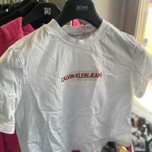Calvin Klein T-shirt  - Vit croppad T-shirt från calvin Klein jeans med röd text, storlek S. Skrynklig på bilden men försvinner om man stryker/tvättar☺️