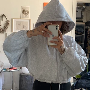 Hoodie croppad  - Grå croppad hoodie med dragkedja och luva , snörning i nedre kant så går att dra åt. Använd några ggr men i bra begagnat skick. 
