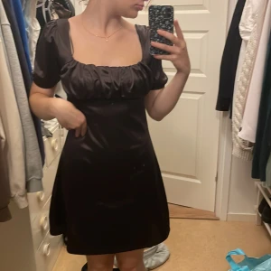 Brun satinklänning - Brun jättefin silkesklänning från hm. Säljer eftersom jag aldrig använder klänningar men impulsköpte denna eftersom jag tyckte att den var fin. Använd ca 2 gånger.