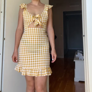 Rutig känning - En söt rutig klänning med knyte över brösten. Har en dragkedja på sidan som funkar som den ska. Tvättas innan köp. Köparen står för frakten.