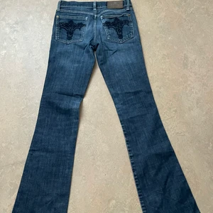 Lågmidjade bootcut jeans med fint tryck där bak - Säljer dessa sjukt fina lågmidjade bootcut jeans då de är för små. Har inga bilder hur de sitter på då de är för små och får ej på mig de. Köparen står för frakten, för fler frågor skriv:)