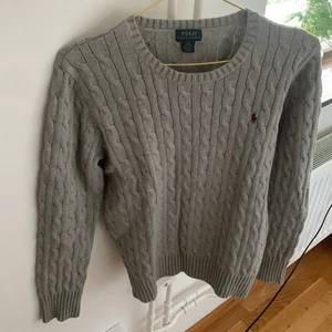 Polo - En grå tjocktröja med rött märke. Den va använd fyra fem gånger och den är inte sönder någon stans 