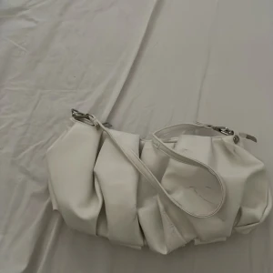 Vit pompig axelväska - Helt okej skick, den har lite skuffs som kan bli lätt borttagna med vatten i lite tvål, bra med utrymmer och jätte fin