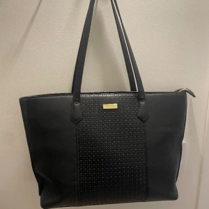 Don Donna Väska -  Säljer denna superfina väska med guld detaljer! Köpt för ca 1 år sen och är i bra skick. Har en liten skada på ena hörnet (se bild) men inget hål. Köpt för 500kr. Köparen står för frakten. Perfekt väska till stranden till sommar!🌟