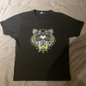 Kenzo t-shirt i storlek L - Säljer en kenzo T-tröja som jag försökt sälja på de flesta ställen utan någon lycka. Vill egentligen bara bli av med den nu. Bra skick, inte avänt den ofta eftersom det inte riktigt är min stil.