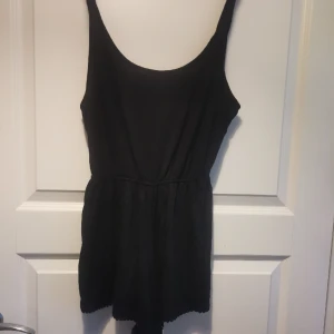 Ursnygg svart shorts onsie - En liten onepiece med korta ben, spetskant och öppen rygg med knytning. Skrynklig men i bra skick 