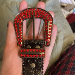 Y2k Bälte - Jättecoolt rhinestone bälte i svart och röd, jättebra skick då de bara andvänts en gång! Den är i storlek 100, alltså 100cm långt. 