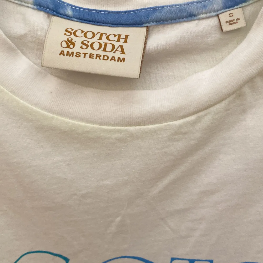 Scotch & Soda T-shirt, vit med blå text, gul rand på armar och nederst. T-shirts.