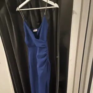 Royal Blue klänning med silver glittriga band i storlek xs-s. Klänningen har en slits i mitten längst ner och är scrunchad på vänster sida. Klänningen har använts 1 gång 