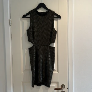 Festklänning med cutouts - Supersnygg klänning med cutouts i midjan. Metallic färg som gör sig väldigt snygg på festen. Storlek S.