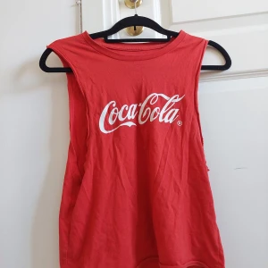 Topp Coca-Cola  - Röd topp med Coca-Cola tryck, urringning vid sidorna. Bra skick!