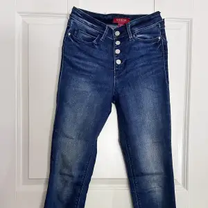 Ett par mörkblåa jeans i storlek 26. Enda defekten är att strassdetaljen på ena fickan börjat lossna.