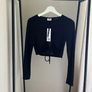 En svart cropped tröja med en rund skurning i mitten som man knyter med snören. Endast provad  