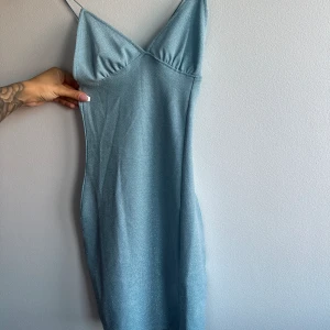 Festklänning  - Ljusblå festklänning med spagetti band. Tajt figurform. Aldrig använd  Xs 