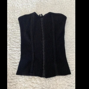 Svart stickad topp utan ärmar  - En söt svart korsett-inspirerad stickad topp!