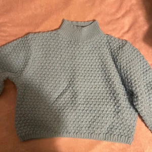 STICKAD TRÖJA - Blå, stickad tröja med lite högre krage och kortare midja. Storlek 40/42. 