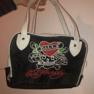 Ed Hardy Väska - Vintage Ed Hardy väska med hjärta detalj. Använd och har en par fixade grejer.