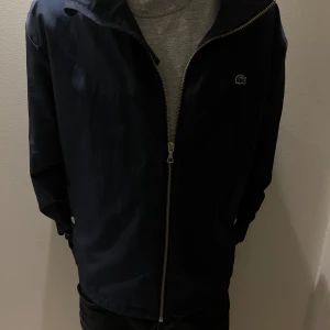 Lacoste jacka - Säljer denna mörkblå Lacoste jacka i storlek M.