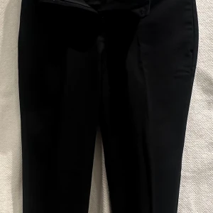 Svarta kostymbyxor från Esprit - Svarta kostymbyxor med stretch från Esprit.  Slits nedtill.   Mått: Midja 37cm Höfter 43cm Längd 91cm Innerbenslängd 65cm Bredd nedtill 15cm