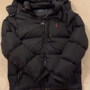 Ralph Lauren vinterjacka ~ water-repellent down jacket - Jackan har använts 2 vintrar i rad, den är jätte varm och skön samt håller värmen inne. Den har ett litet hål vid ena ärmfickan (se slide 5) och bröstfickan samt ena ärmfickan så sitter dragkedjan fast vilket kan fixas enkelt. 