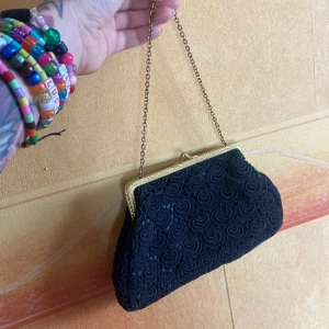 Fest väska  - Lite vacker spetts väska med guld kedja samt kant. Så söt till fest, bal eller bröllop. Man kan ta me de vesäntliga.  Den är ungefär 21 nertill och ca 13 upptill x 13 hög.  Tror ja har fått denna av min mormor.  Jag har aldrig använt den själv.