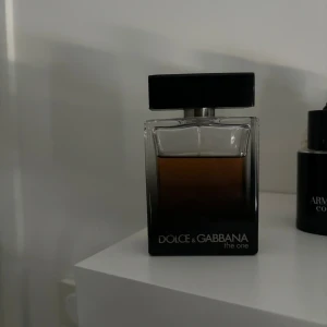 Dolce & Gabbana The One For Men Eau de Parfum - Dolce & Gabbana The One For Men Eau de Parfum är en lyxig herrparfym med en elegant och maskulin doft. Flaskan är rektangulär med en mörk gradient från svart till genomskinlig glas och har en svart fyrkantig kork. Parfymen är tillverkad i Frankrike och innehåller 100 ml (3.3 FL. OZ.).