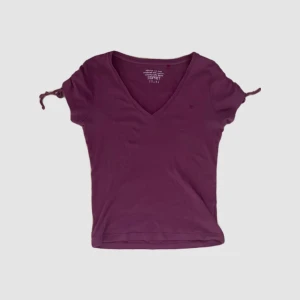 Lila topp med rynkade detaljer - En lila topp med v-ringning och rynkade detaljer på ärmarna. Toppen har korta ärmar och en åtsittande passform.