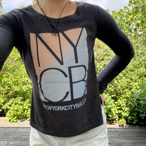 Långärmad NYC-balett tröja - Unik, mörkgrå NYC-balett tröja med tryck! 🩰Tröjan har delvis öppna sidor och är längre bak än fram (visas på bild 2). Köpt i New York! Storlek: S. Material: 52% bomull + 48% polyester. Nyskick! Använd en gång! :)