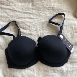 Svart bandeau BH med avtagningsbara band - Svart bandeau BH med avtagningsbara band från Lindex. Helt oanvänd med prislappen kvar! Passar prefekt att ha under en bandagetopp om man tar bort banden, annars prefekt som vardaglig BH.