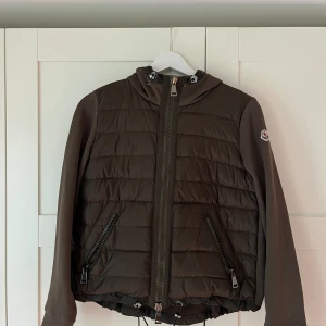 Moncler jacka - Maglia Cardigan Olivgrön/brun/khaki  Skicket givetvis mer bilder på att den är verifierad äkta av moncler  Knappast använd  100% polyamid, 100% bomull, 90% dun och 10% fjäder Modellen med färgen görs inte längre 