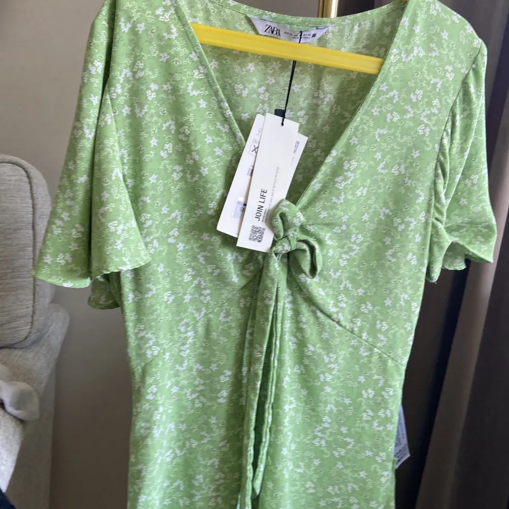 Söt grön zaraklänning knuten vid bysten med rosett. . Mekot.