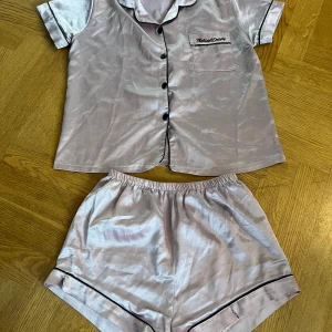 Rosa silkes pyjamas  - Rosa silkes pyjamas, använd några gånger, har en liten ficka på tröjan, shortsen har gått sönder lite på två ställen