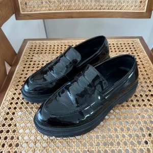 Lackade loafers - Lackade loafers i faux leather. Lite repiga på insidan av skon (sista bilden) annars i bra skick!