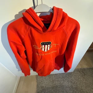 Gant Hoodie  - Säljer nu min röda Gant hoodie då den börjar bli för liten. Hoodien är i ett väldigt fint skick (9/10) och sparsamt använd. Modellen på bilden är 174 cm lång.  Nypris på hoodien ligger runt 700-900 kr. Jag säljer den för 150 kr, haft den ett tag.  