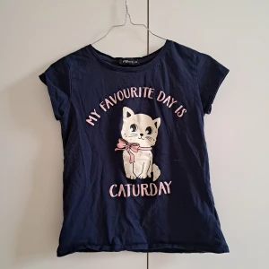 T-shirt med tryck - T-shirt med tryck "My favourite day is Caturday" från New Yorkers kollektion "FB sister" // Någon lite lös tråd vid armen på insidan, annars i gott skick // 100% bomull // Skicka pm för mer info/samtal