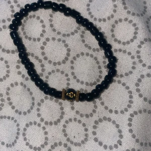 Svart armband med kors! - Handtillverkat armband! Elastiskt och Basic armband med ett guldigt kors på. 