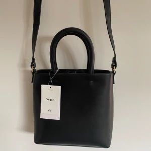 Väska - Säljer denna oanvända axelremsväska från hm i veganskt läder som har lappen kvar❤️ skriv för fler bilder. Ordinarie pris 229kr 