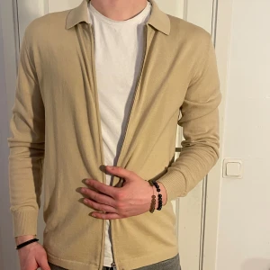 Finstickad kofta J.Lindeberg Merino Cardigan - Beigie Finstickad J.Lindeberg Kofta av 100% merinoull i smal passform. Helt ny skick med prislapp kvar! Storlek L men passar som M och även stor S. Modellen är 182 cm och väger 75 kg. Nypris: 1800 kr. Pris går att diskuteras!