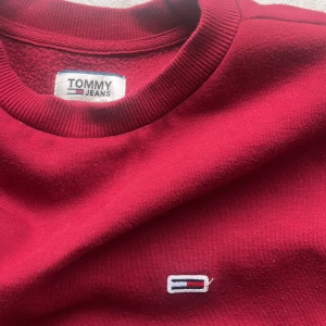 Tommy Hilfiger Sweatshirt - En helt oanvänd Tommy hilfiger sweatshirt. Skulle säga att den är mindre röd i verkligheten. Det är ett varmare material på insidan. Köptes för 800 och aldrig använd därav priset men kan sänkas då jag verkligen vill bli av med den💕