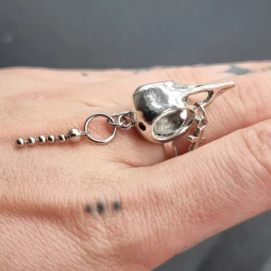 Unik ring med en kråkskalle  - Unik ring med en kråkskalle● Material: metal. Stommen är ca 15mm i diameter, men kan göras mindre eller större, efter behov. Det är bara att försiktigt klämma ihop eller dra isär ändarna baktill, till önskad storlek. Mått på plattan 3cm 