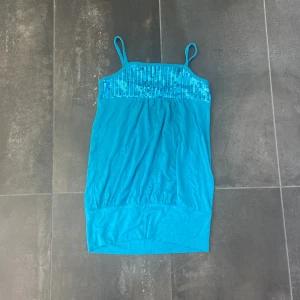 Topp - Glittrigt blått linne från barnavdelningen på Kappahl. Perfekt till som en fest topp. Den motsvarar xxs i vuxen strl men passar även upp till small. Säljer pga av att axelbanden är för korta för mig och är använd några enstaka gånger