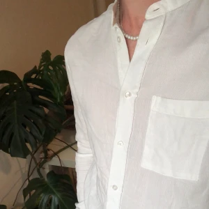 Vit skjorta  - Tunn skjorta utan krage. Väldigt skön att ha på sommaren. Modellen på bilden är 172. Hör av dig vid frågor eller annat! 