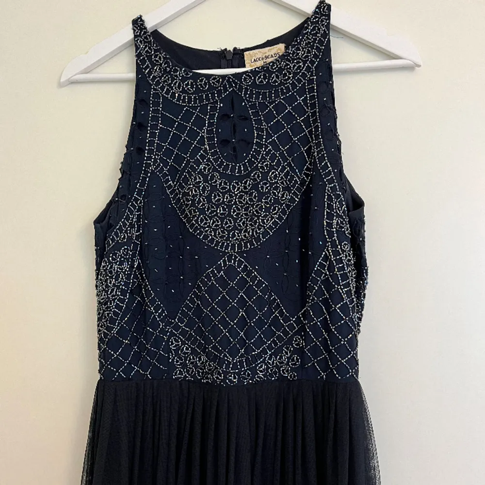 Festlig mörkblå långklänning med vackra detaljer från Lace & Beads, storlek M. Klänningen är som ny, använd enbart 2 ggr.  Dragkedja bak. Paljetter fram och bak.   Mått: längd ca 150 cm, midja ca 37 cm, byst ca 45 cm. Klänningar.