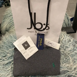 Ralph lauren t-shirt - Supersnygg Ralph lauren t-shirt perfekt till både vintern och sommaren. Köptes nyligen i affär för 899 kr och använd 2 gånger. Inga deffekter och såklart nytvättad. (Allt på bilden ingår). Färgen är en blandning mellan svart och grå, loggan är grön.