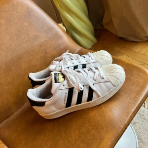 Adidas superstar sneakers 38 1/2 - Trendiga sneakers, Adidas superstar. Helt nytvättade, lossnat lite i  framtill men kan med enkelhet bara limmas fast. Sulorna lite slitna, behöver bytas ut. I övrigt fint skick! 