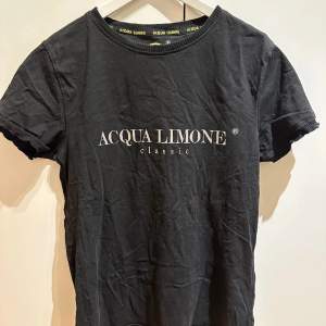 Utforska Aqua Limone’s klassika svarta t-shirt i storlek M med en lätt passform, vilket gör den ganska baggy och bekväm. Ganska få användningar och håller därav hög kvalité. En allsidig bas i garderoben och perfekt till sommaren. Uppgradera stilen!