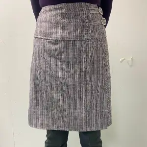 Randig kjol med två bälten på sidan. Även en knapp på innersidan också.